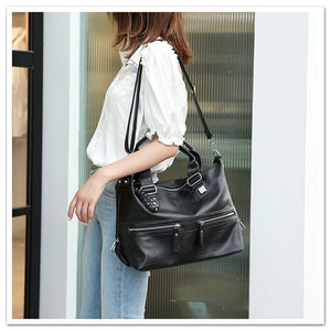 Detail of black pebbled leather tote bag with silver zippers shown on model shoulder