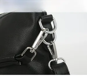 Detail of silver metal hook and D-ring on black lychee leather crossbody bag strap