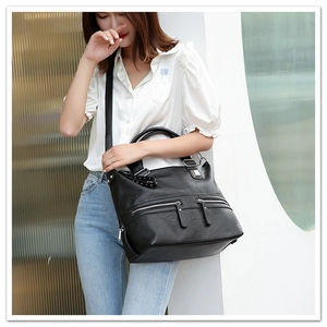 Detail of black pebbled leather tote bag with silver zippers and rivet decorations
