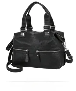 Detail of black pebbled faux leather bag showing silver zippers and textured material