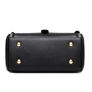 Bottom view of a black leather handbag with four protective gold metal feet studs