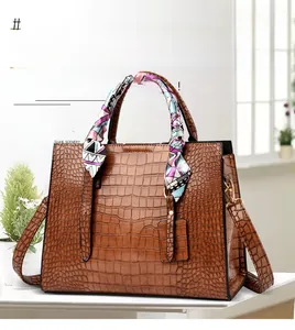 Close-up of brown crocodile texture handbag with silk scarf detail and long strap