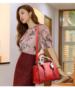 Elegant red crocodile texture handbag with floral scarf handle shown on a model