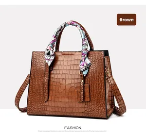 Close-up of brown crocodile embossed handbag with colorful silk scarf wrapped around handle