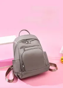 Vue détaillée d'un sac à dos de voyage gris imperméable avec poches zippées sur fond rose