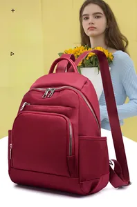 Détail du sac à dos en nylon bordeaux imperméable avec plusieurs poches zippées sur fond jaune