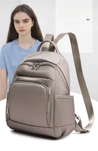 Vue détaillée d'un sac à dos en nylon taupe avec plusieurs poches et des fermetures argentées