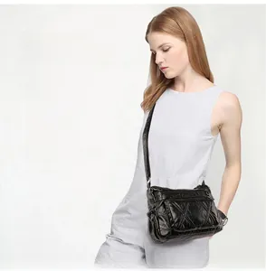 Detailed view of black washed leather crossbody bag with multi-zipper compartments on model