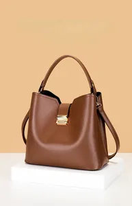 Détail d'un sac seau en cuir marron avec boucle en métal doré sur un piédestal blanc
