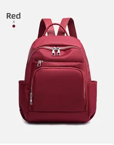 Détail d'un sac à dos de voyage en nylon rouge imperméable avec plusieurs poches zippées
