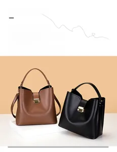 Détail de sacs seaux en cuir grainé avec fermoirs rotatifs métalliques en marron et noir