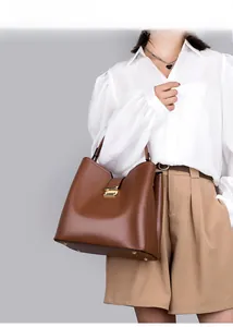 Vue détaillée d'un sac seau en cuir marron avec pieds dorés et fermoir métallique