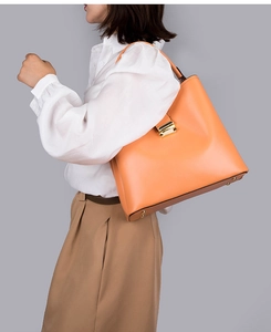 Détail du sac à main en cuir orange chaud avec boucle dorée sur un mannequin professionnel