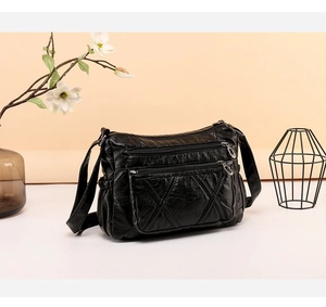 Detail of black soft leather crossbody bag showing multi-layer zippers and stitching