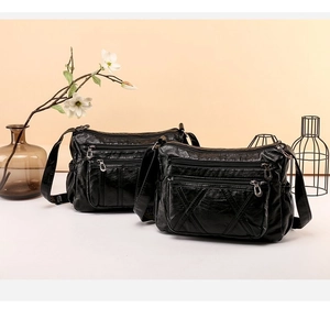 Detail view of black soft PU leather crossbody bag featuring a multi-zippered design