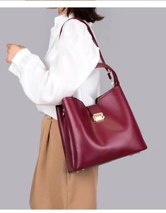Détail du sac seau en cuir bordeaux avec boucle dorée présenté de profil sur un mannequin