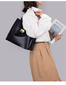 Vue latérale du mannequin portant un sac seau en cuir noir avec boucle dorée élégante