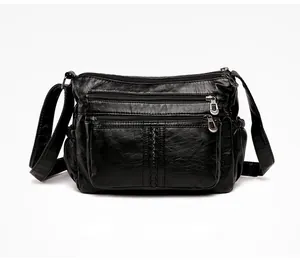 Detail view of black PU leather handbag featuring three parallel zip pockets and texture