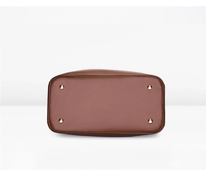 Détails du fond d'un sac en cuir marron avec quatre pieds de protection en métal doré