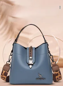 Detail of blue-grey leather bucket bag featuring lychee texture and jacquard shoulder strap