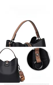 Detail of black pebbled leather bucket bag with brown handles and embroidered strap