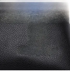 Macro detail of black textured leather featuring a silver kangaroo metal logo and brand emblem