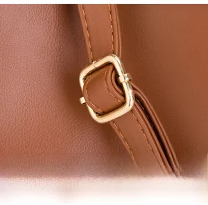Détail de la bandoulière réglable en cuir marron avec boucle en métal doré et coutures