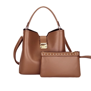 Détail d'un ensemble sac seau marron avec boucle dorée et pochette cloutée assortie