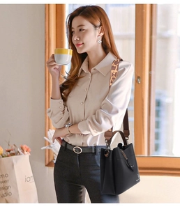 Detail of a black pebbled leather bucket bag with a brown patterned wide strap on a model