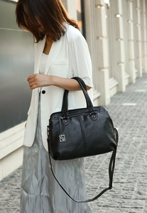 Close-up of a black PU leather handbag with lychee texture and silver metal pendant