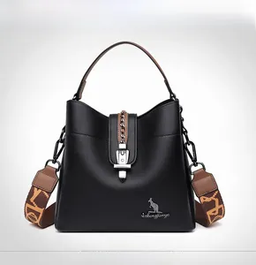 Detail of black pebbled leather bucket bag with brown handle and patterned strap