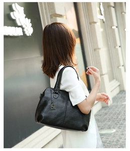 Outdoor street view of a black large capacity PU leather tote bag with a fashion pendant