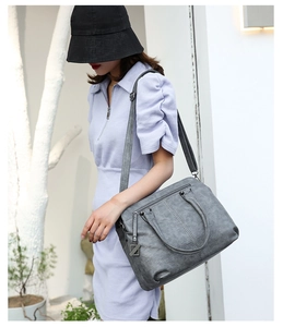 Detail of grey PU leather tote bag with decorative zippers and adjustable strap