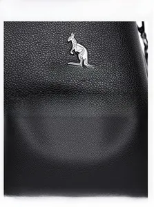 Detail shot of black pebble grain leather handbag with silver kangaroo logo and fine stitching