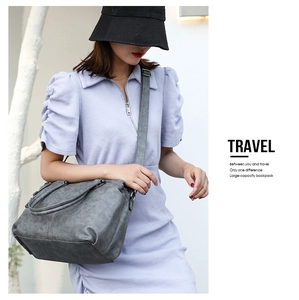 Outdoor shot of a grey large capacity leather travel bag with a model in purple clothing