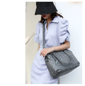 Gray travel handbag featuring dual handles and adjustable shoulder strap for women