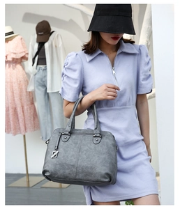 Close-up of grey leather tote bag with pebble texture and front zipper detail