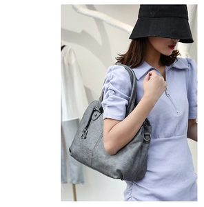 Detail of grey PU leather tote bag with V-shaped metal pendant and textured finish