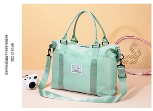Detail of mint green waterproof travel bag with dual handles and detachable shoulder strap