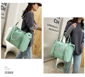 Detail of mint green nylon travel tote bag showing adjustable shoulder strap and dual handles