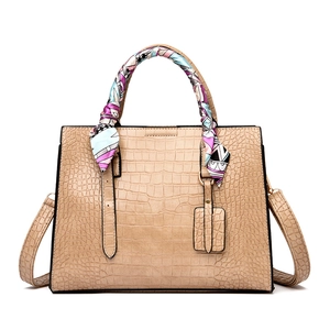 Detail of beige crocodile embossed tote bag with colorful silk scarf wrapped on handle