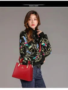 Red leather handbag with gold buckles shown on female model with printed sweater