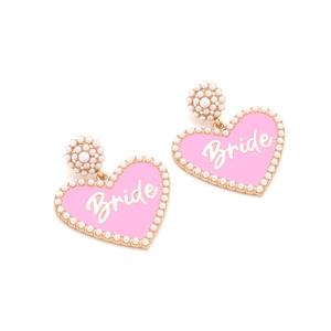 Macro detail of pink heart earrings with faux pearl border and golden Bride text