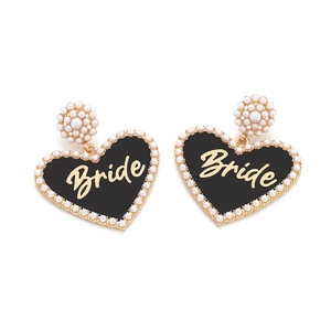 Detail of heart-shaped bride earrings with black enamel, pearls and gold lettering