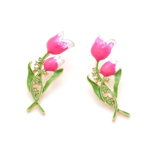 Détail de boucles d'oreilles tulipes émaillées roses avec zircons verts et or