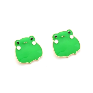 Detailed close-up of cute green enamel frog stud earrings with gold trim and cartoon eyes