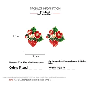 Macro detail of strawberry enamel earrings showing zinc alloy plating and rhinestone inlay