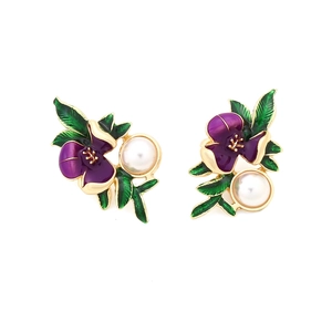 Gros plan de boucles d'oreilles fleurs en émail violet avec perles et pétales dorés