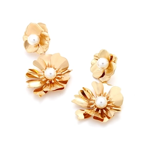 Detailed macro of gold double-flower earrings featuring central white pearls