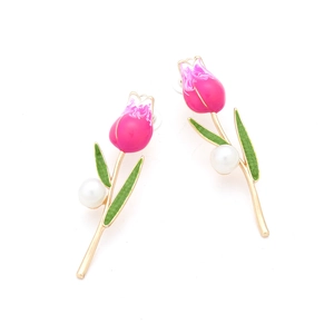 Detail of pink enamel tulip earrings with green leaves, gold stems and pearl accents